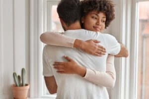 זוג מחובק ליד החלון — שיפור תקשורת זוגית בכלי NLP