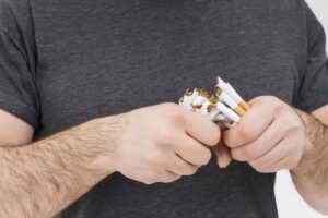 גבר שובר סיגריות בידיו — גמילה מעישון בעזרת טיפול NLP